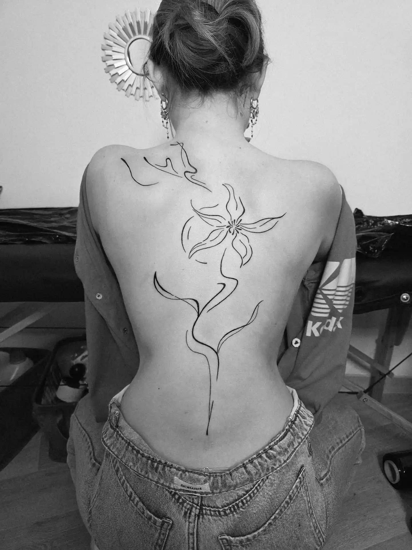 Tatouage floral fine line dans le dos - fleur en traits délicats